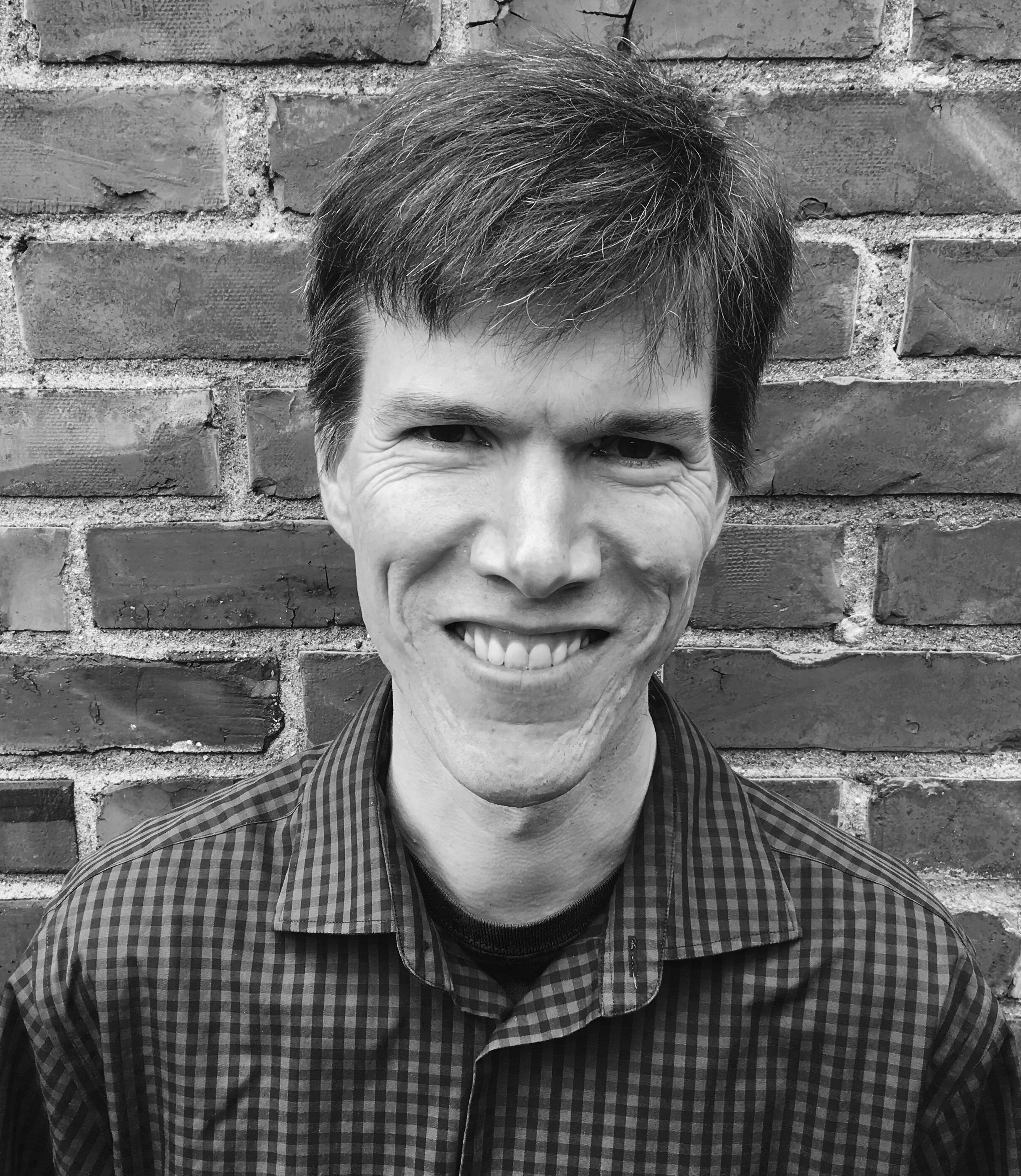 Black and White Photograph of Peter Blossey in front of a brick wall